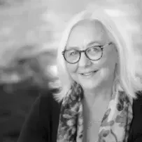 A black and white photo of a woman wearing glasses and a scarf.