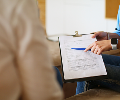 A woman is sitting on a couch holding a clipboard and a pen.