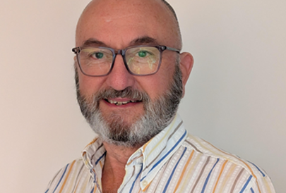 A man with a beard and glasses is smiling for the camera.