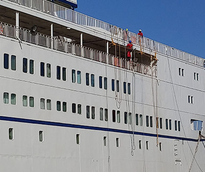 Two men are working on the side of a large white ship