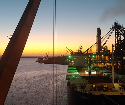 A large ship is docked in a harbor at sunset