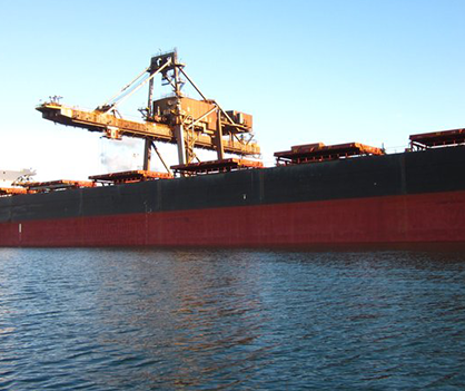 A large red and black ship is in the water