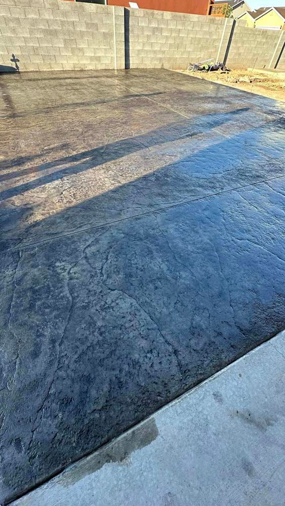 A concrete driveway with a brick wall in the background.