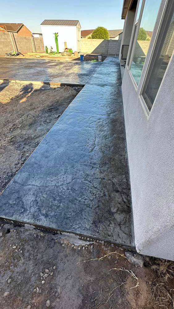 A concrete walkway is being built in the backyard of a house.