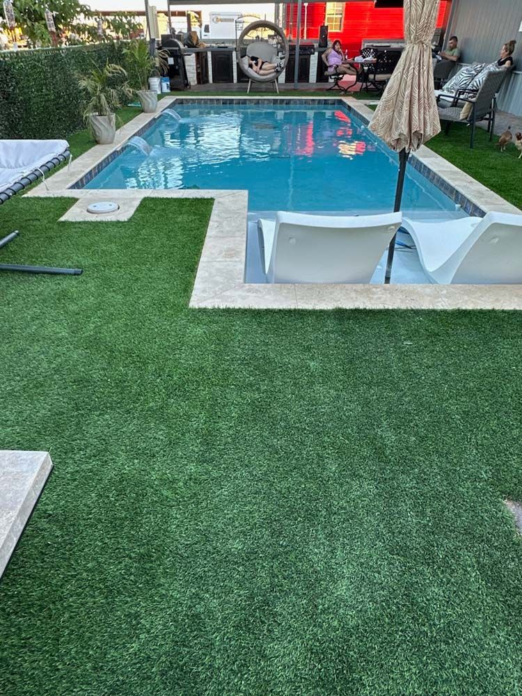 A large swimming pool surrounded by chairs and umbrellas in a backyard.