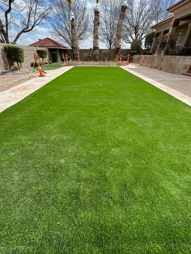 A lush green lawn with a walkway leading to a house.