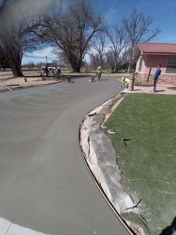 A group of people are working on a concrete driveway.