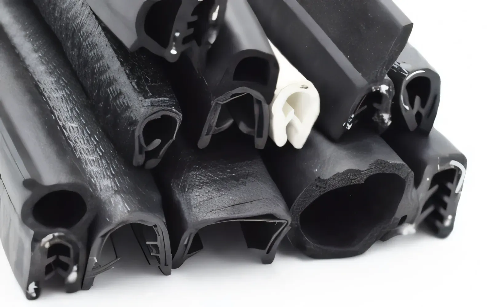 Black rubber seals of various shapes, piled together. One is white.