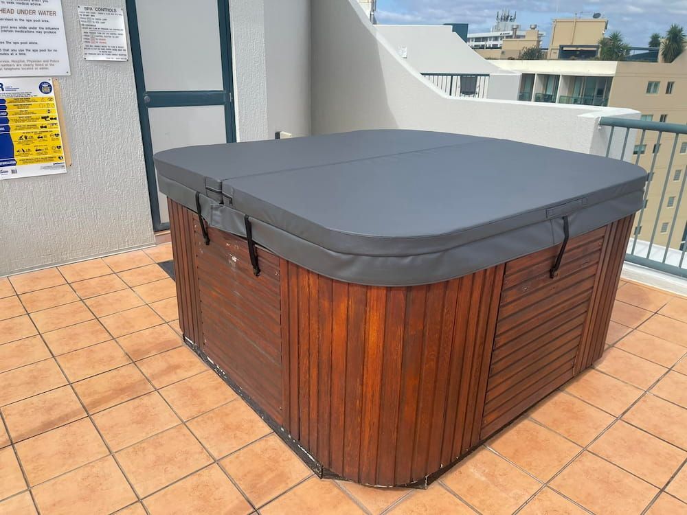 A Wooden Hot Tub With a Black Cover is on a Tiled Deck — F.R.I. Foam & Rubber Industries In Buderim, QLD