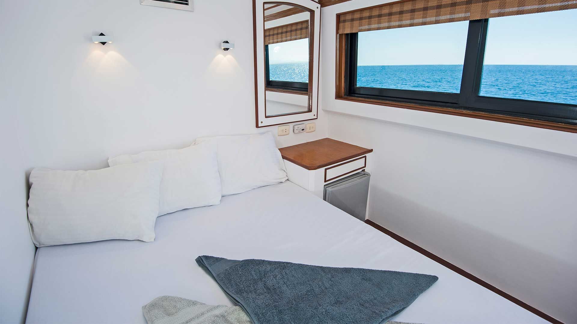 Bedroom interior with white walls, bed, window with ocean view.