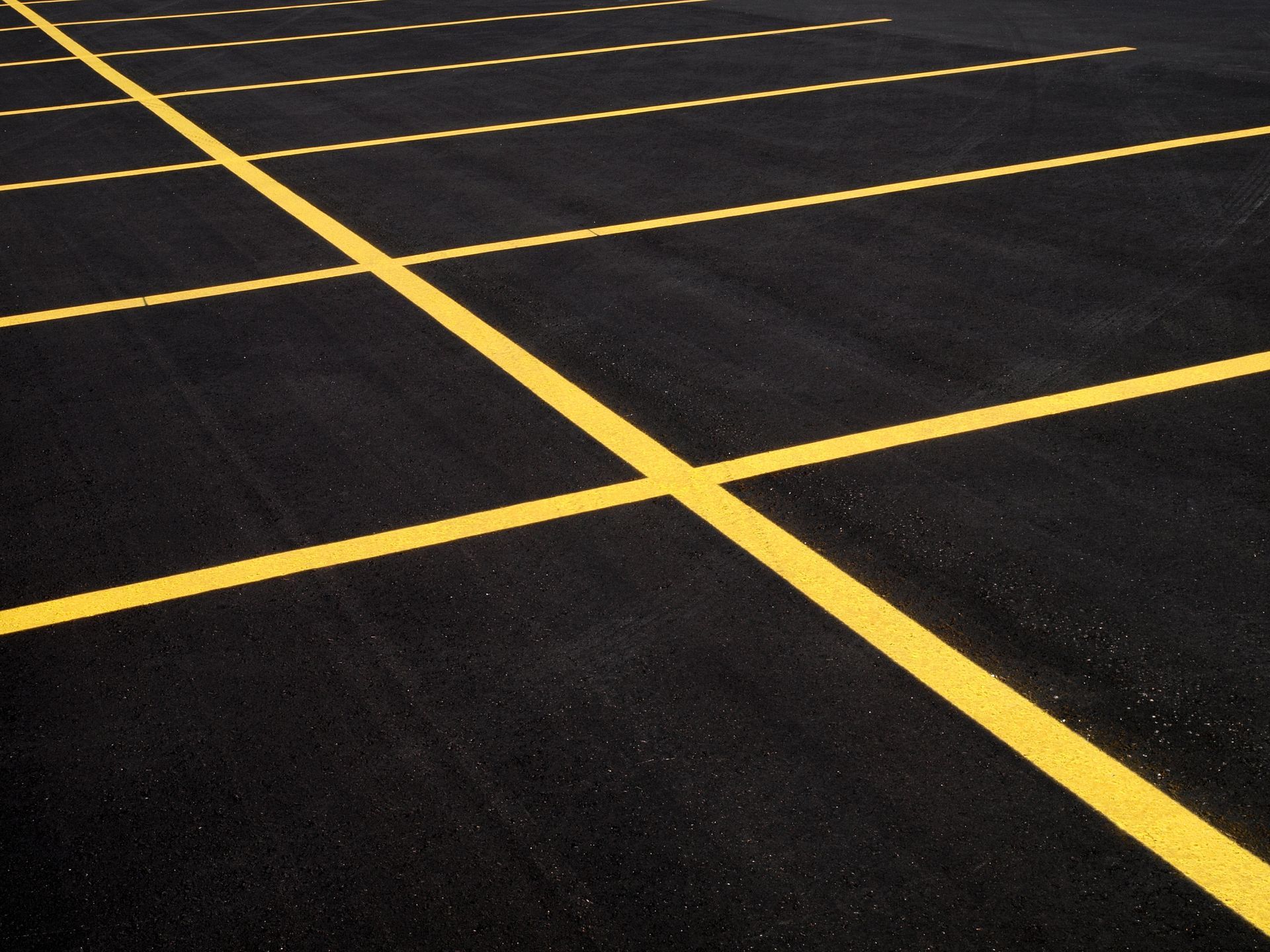 Yellow parking space lines on black asphalt, diagonal view.