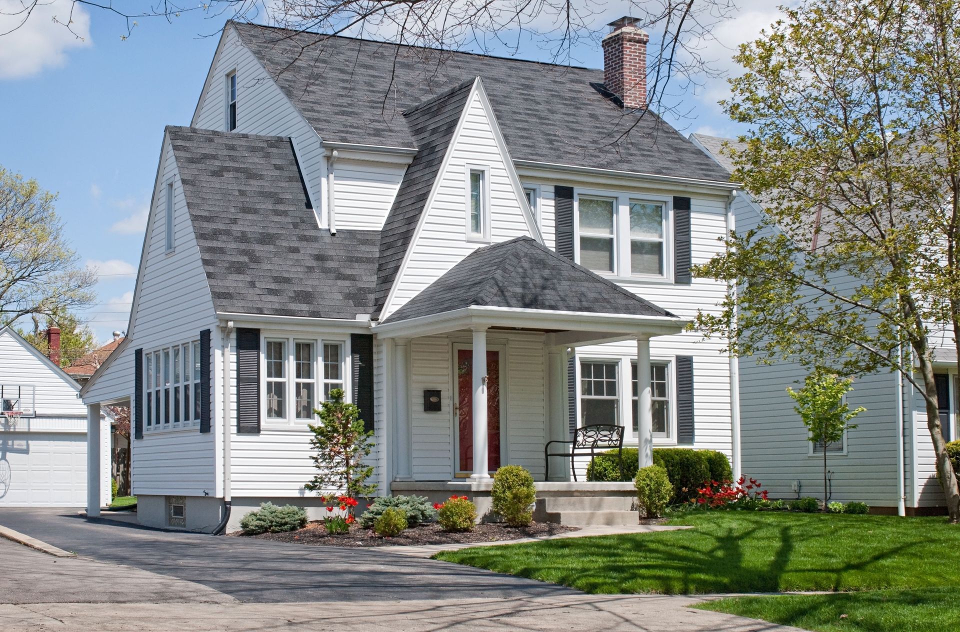 Rear exterior with open glass doors, patio furniture, and yard with gray pavers and grass.