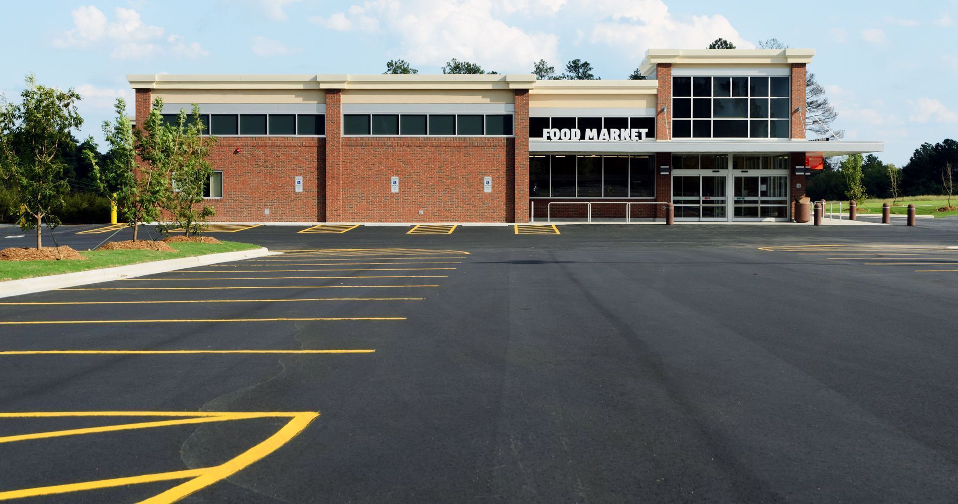 Building with large glass windows next to a waterway with trees, under a clear sky.