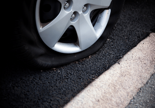 Flat tire on car parked along roadside curb
