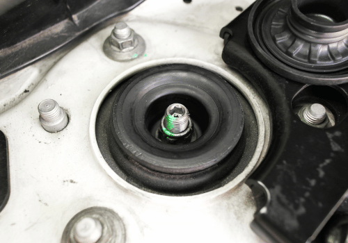 Close-up of worn strut mount and suspension component in engine bay