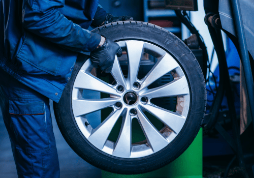 Auto technician holding a vehicle tire during wheel balancing and tire service