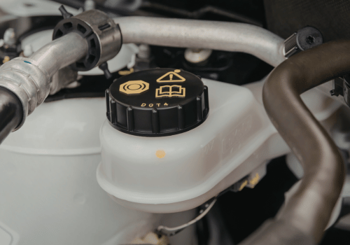 Close-up of a brake fluid reservoir with a cap labeled DOT 4 inside a vehicle engine bay.