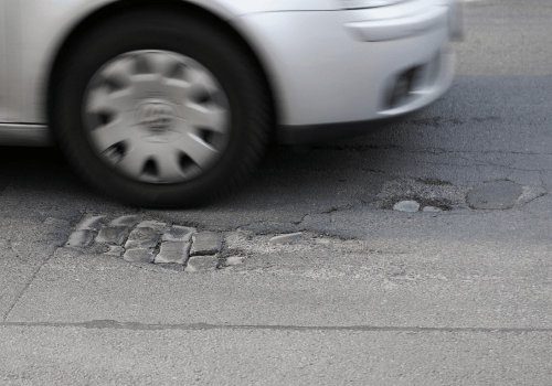 Car driving over a pothole, illustrating suspension impact and potential clunking noise.