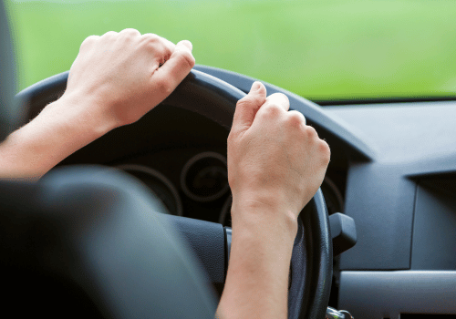 Driver gripping steering wheel, representing vibration or shaking while driving.