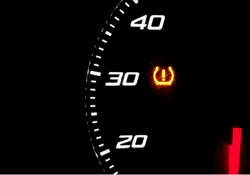 Dashboard gauge showing illuminated tire pressure warning (TPMS) light.