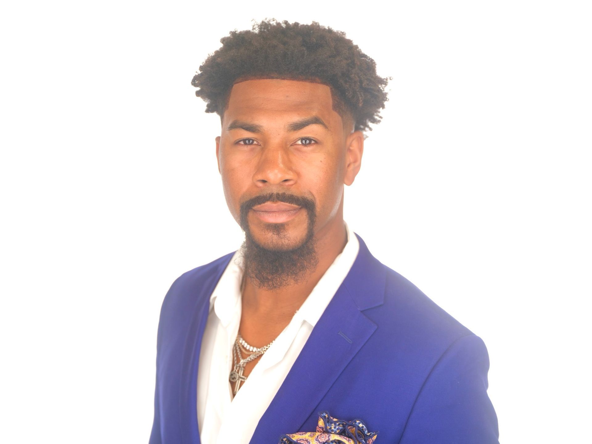 A man with a beard is wearing a blue suit and white shirt.