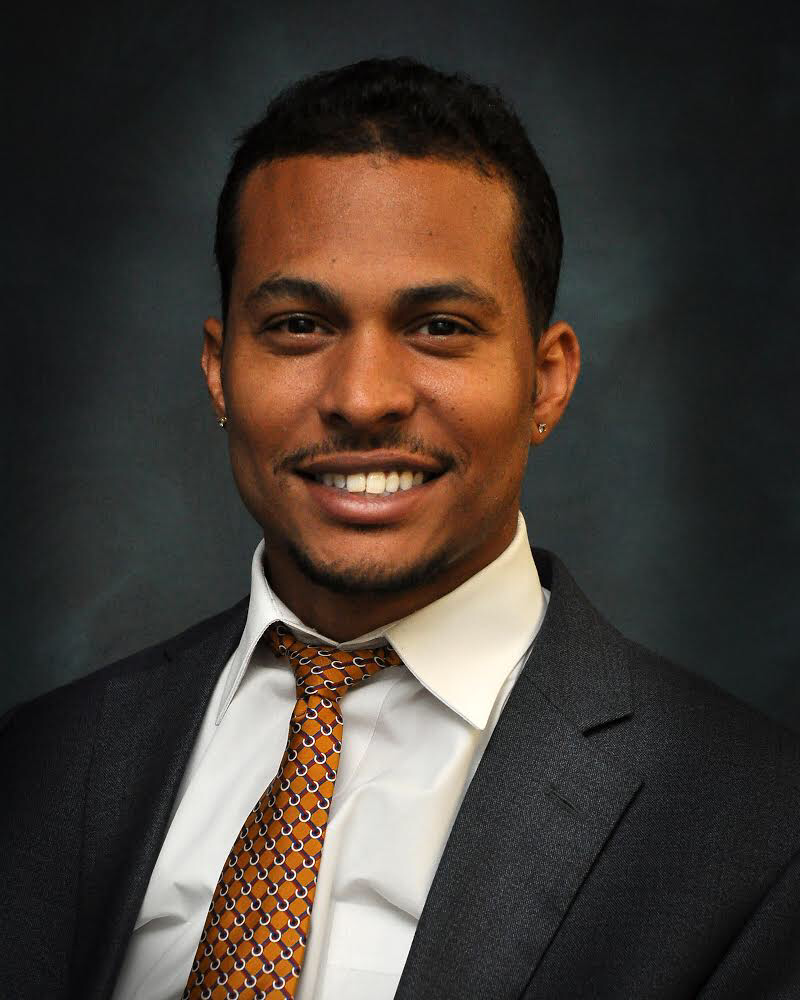 A man in a suit and tie is smiling for the camera