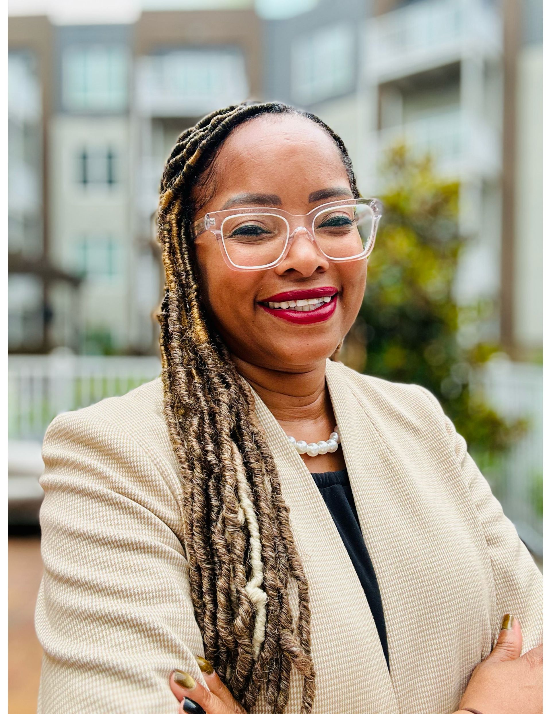 A woman wearing glasses and a pearl necklace is smiling for the camera.
