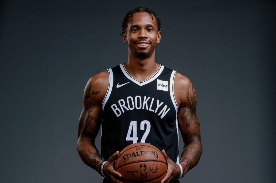 A man in a brooklyn nets jersey is holding a basketball.