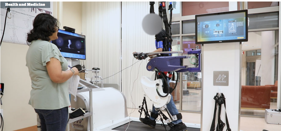 A woman is standing next to a robot on a treadmill.