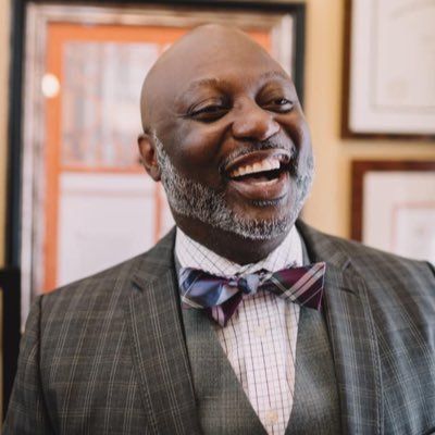 A man in a suit and bow tie is laughing.