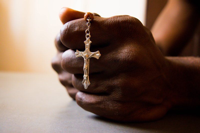 individual holding a cross sign and reading a religious book