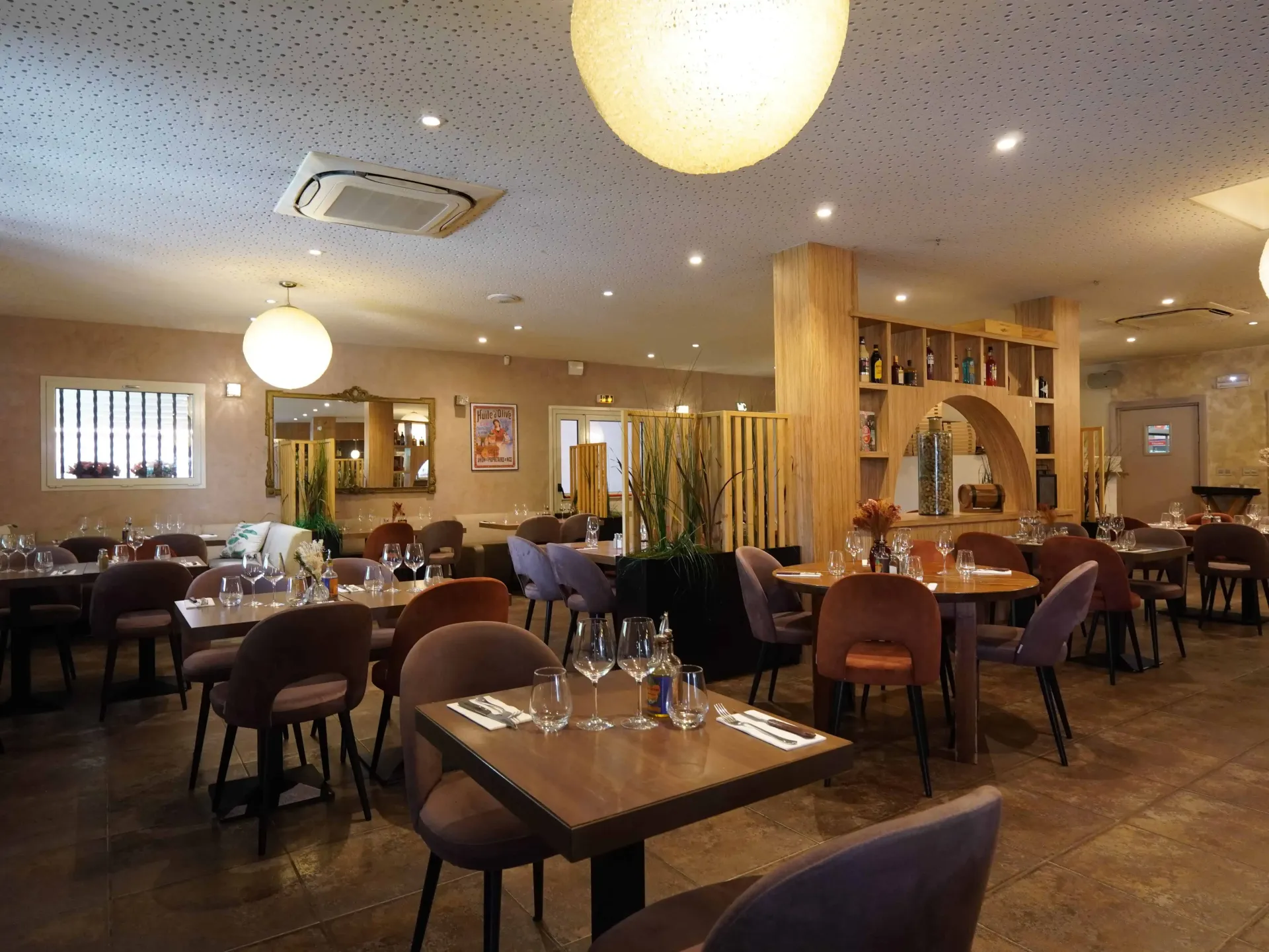 Restaurant : tables, chaises, éclairage décoratif. Couleurs douces et neutres, quelques tables vides.