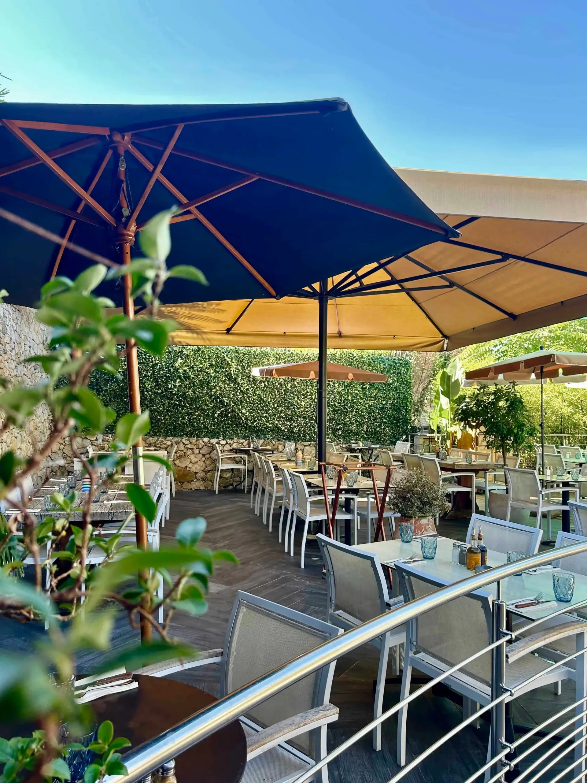Terrasse de restaurant extérieure avec tables, chaises et parasols.