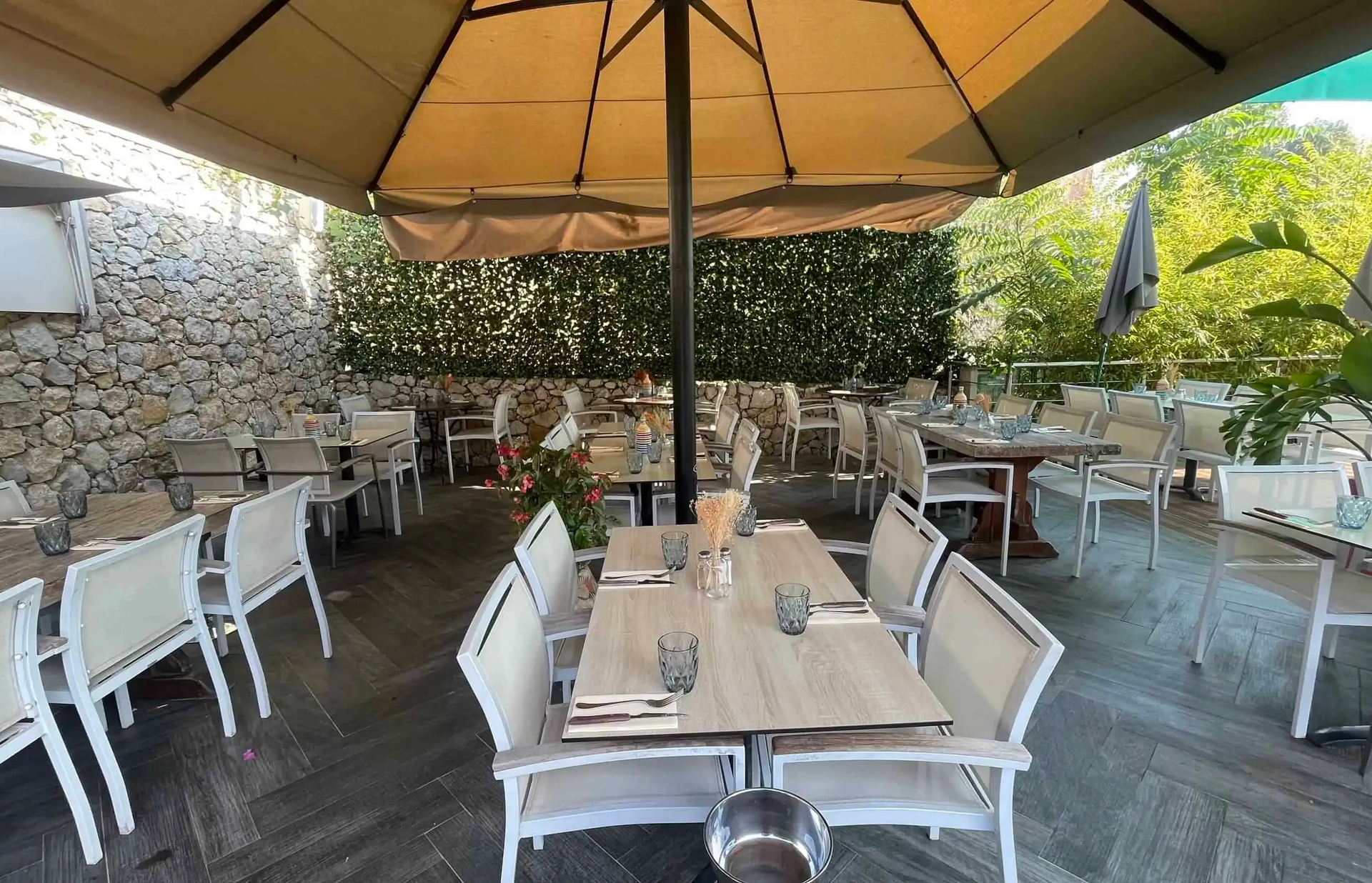 Espace de restauration extérieur avec tables, chaises blanches et parasols.