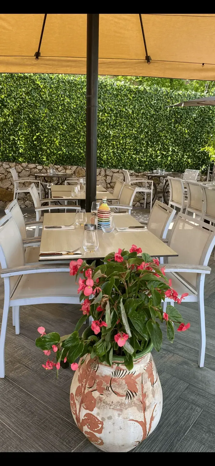 Restaurant extérieur avec tables, chaises et pot de fleurs décoratif.