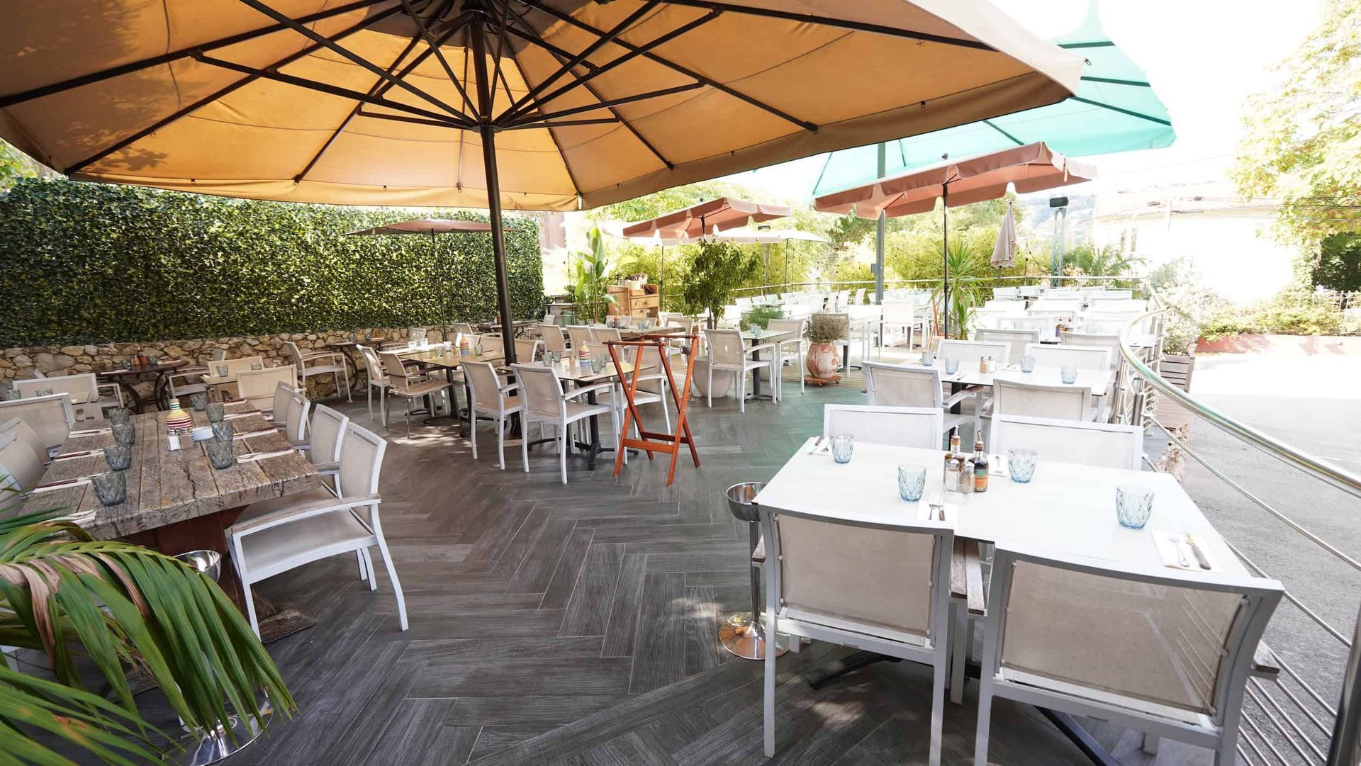 Terrasse extérieure de restaurant avec tables, chaises et parasols.