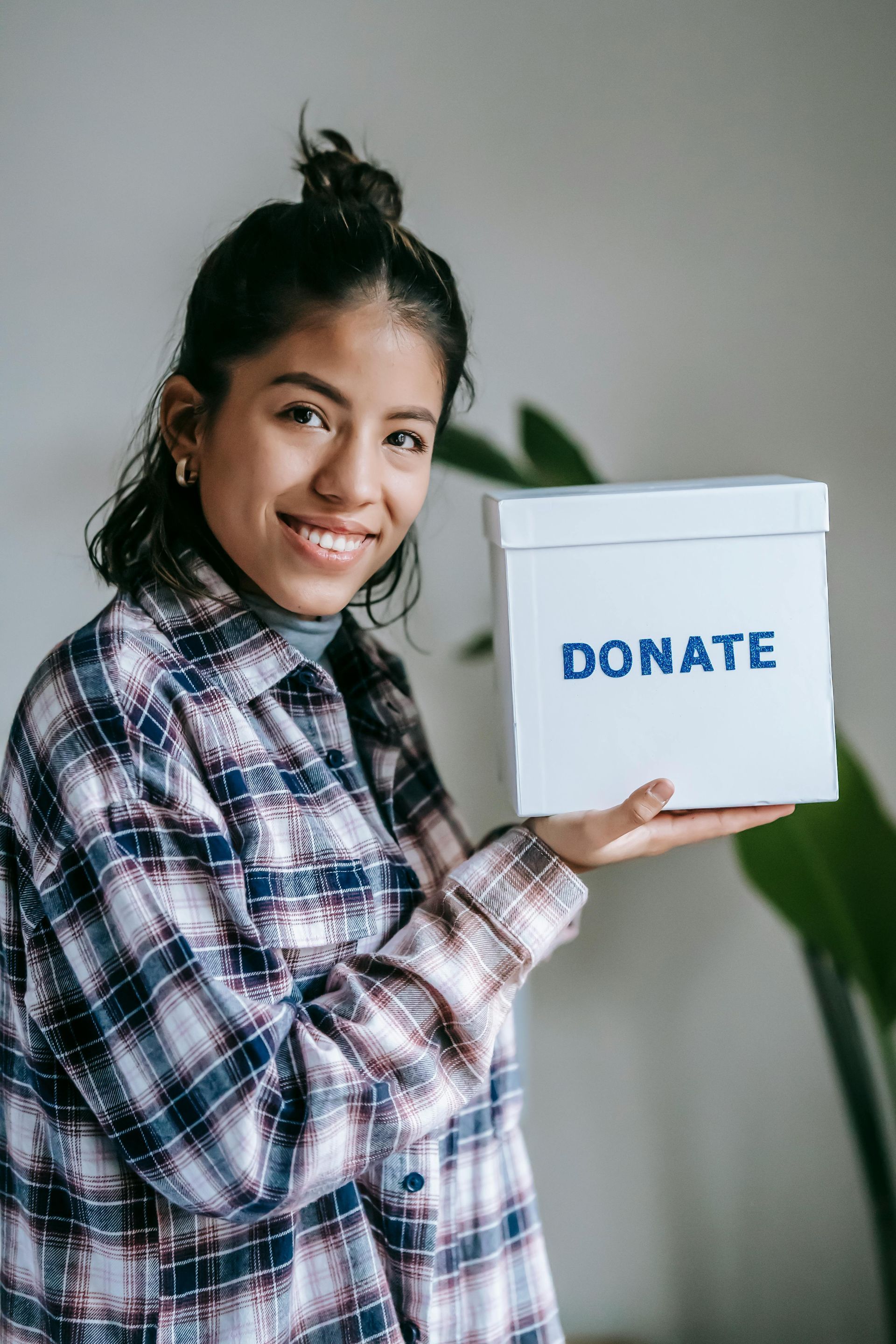 A woman is holding a white box that says `` donate ''.