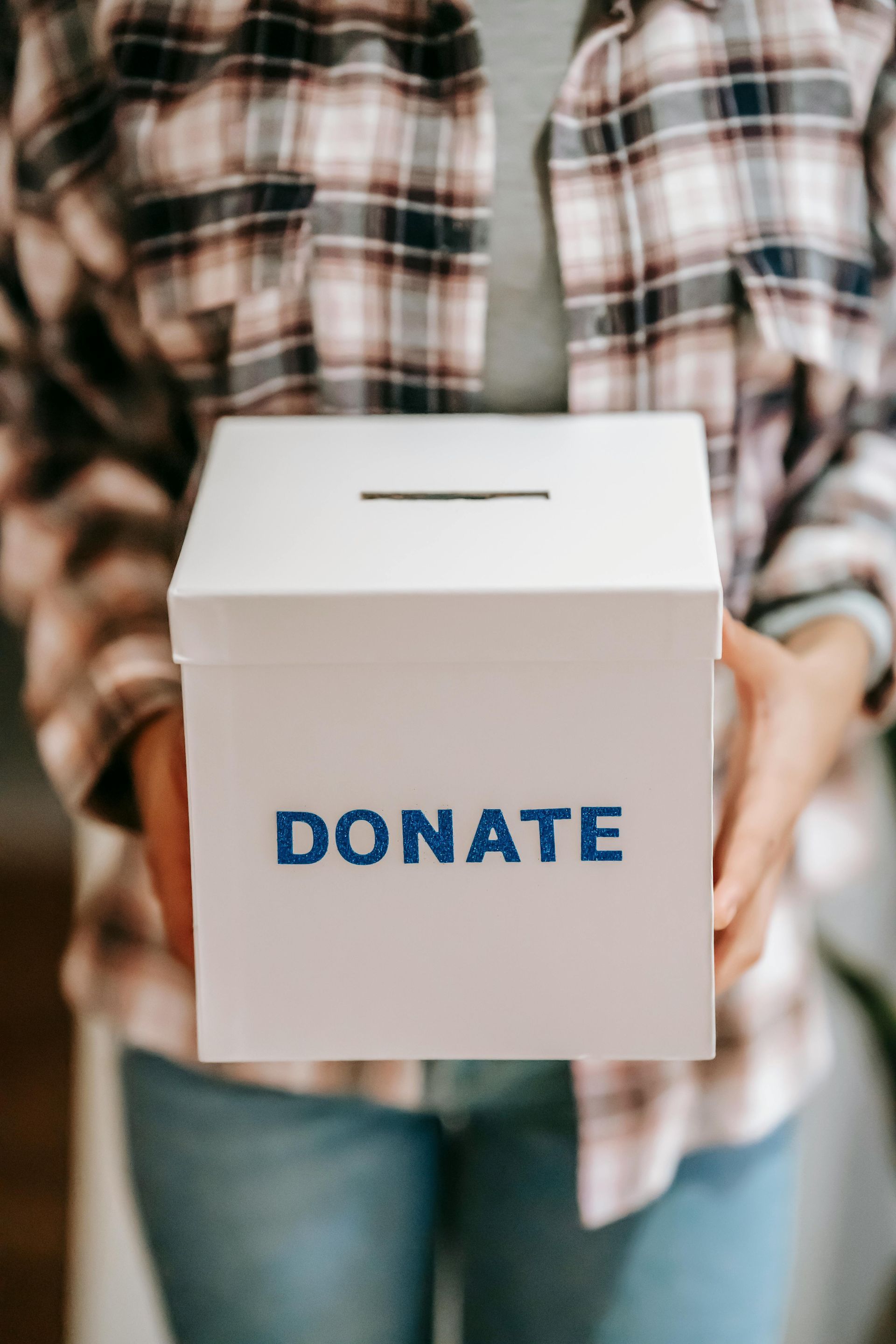 A woman is holding a white box that says `` donate ''.