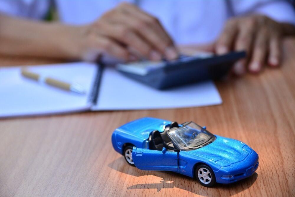 A Blue Toy Car Is Sitting On A Wooden Table Next To A Person Using A Calculator — Summit Smash Toongabbie In Toongabbie, NSW