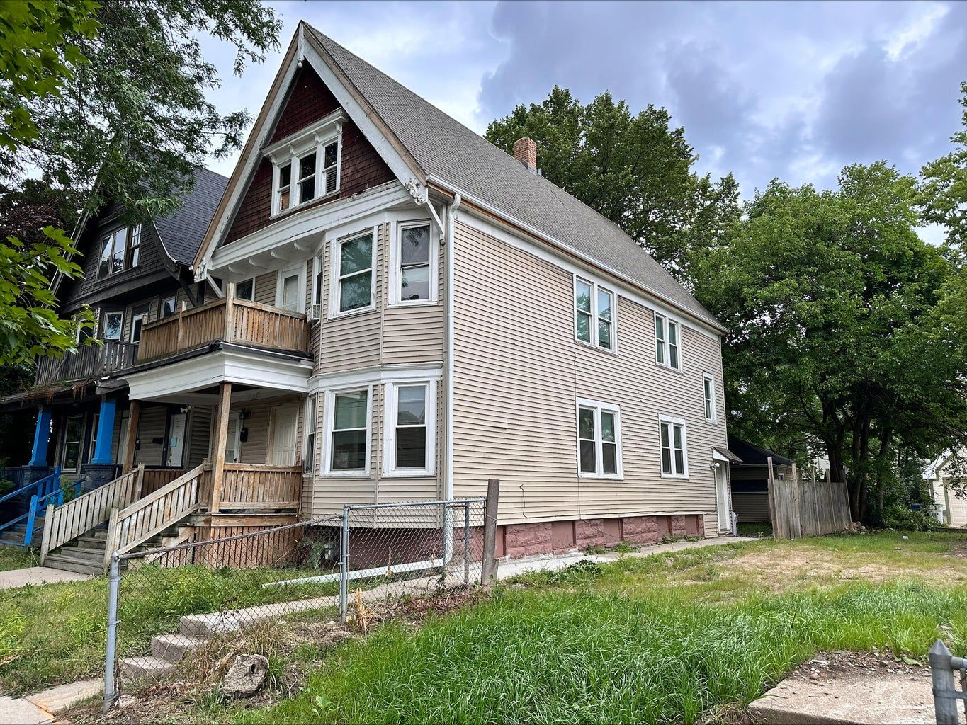 A large house with a lot of windows is sitting in the middle of a lush green field.