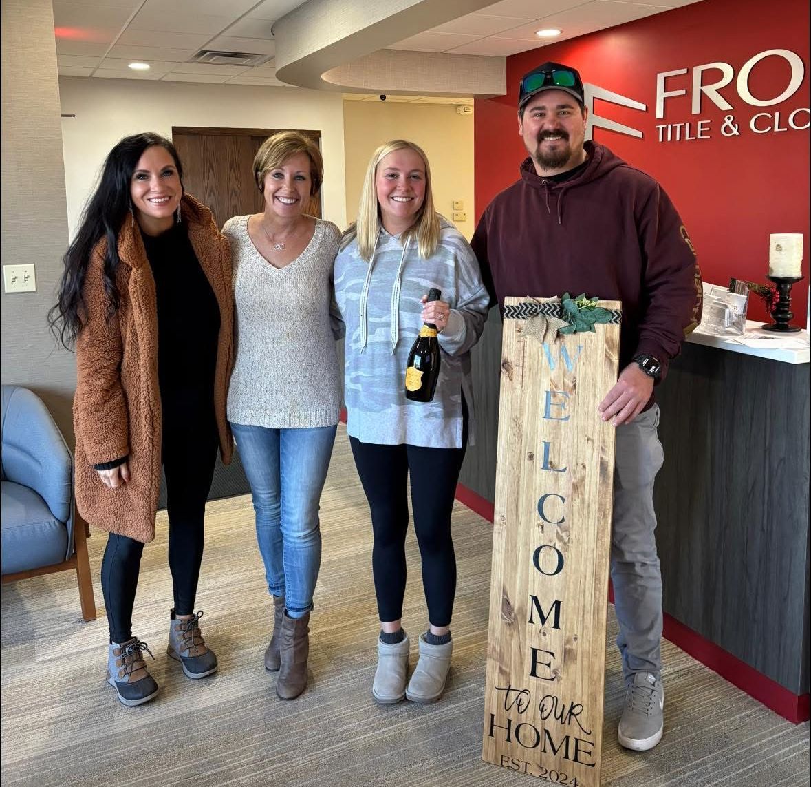A man and woman holding a sold sign in front of a house