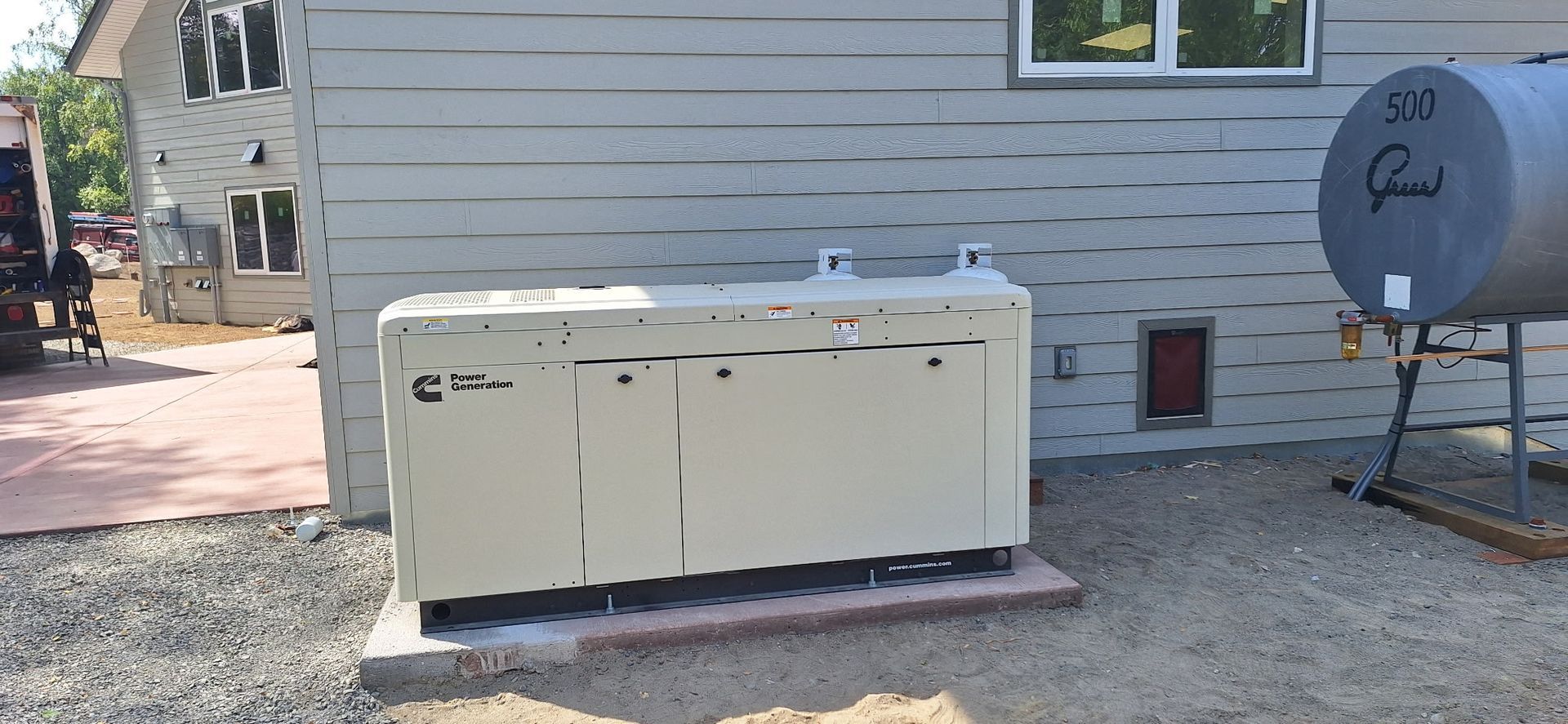 A black portable generator with green controls in front of a Kingdom Electric LLC sign.