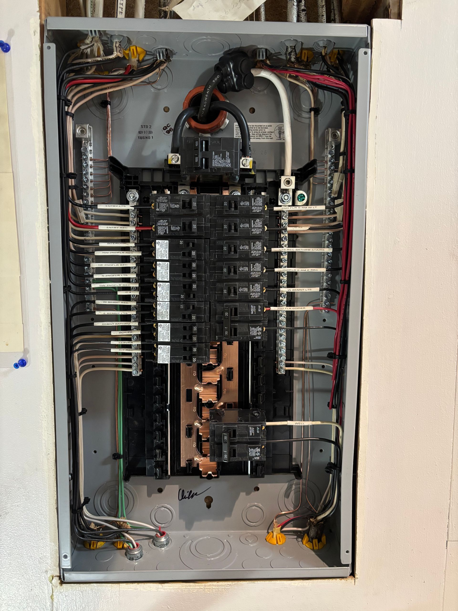 Electrical panel with numerous circuit breakers and wiring.
