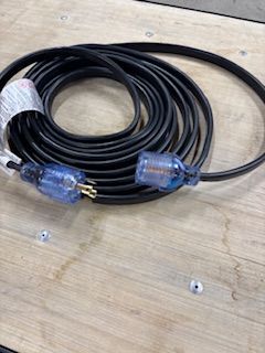 Coiled black extension cord with blue ends, on a wooden surface.