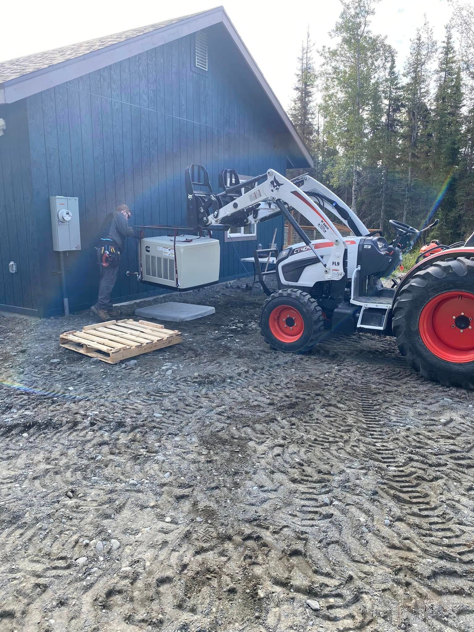 A worker and tractor lift HVAC unit to install it on a blue building.