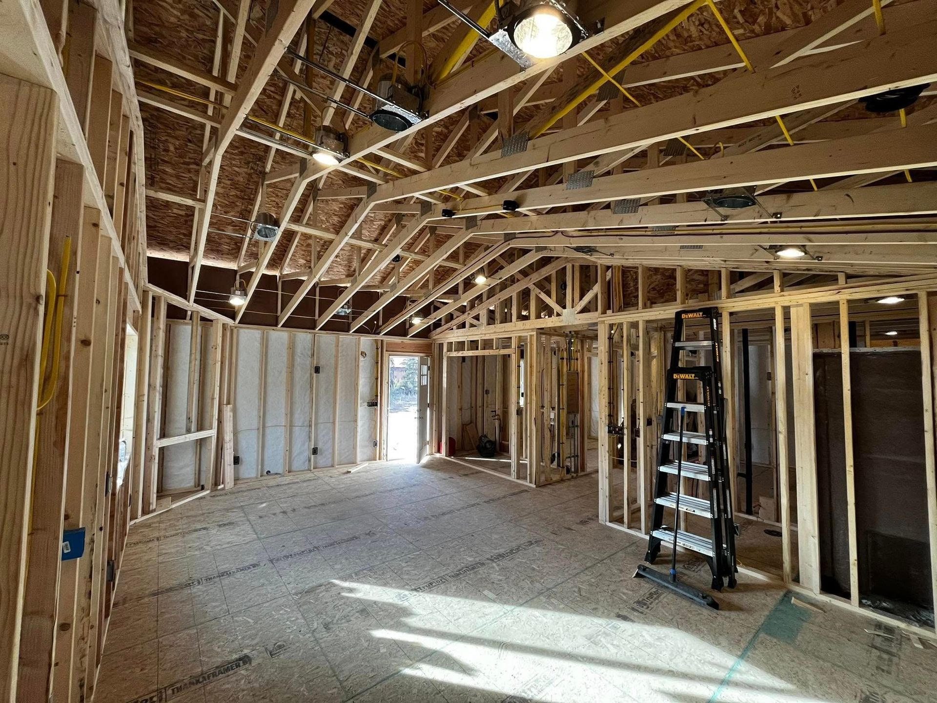 Interior of a building under construction; wooden frame, exposed beams, unfinished walls, and a ladder.