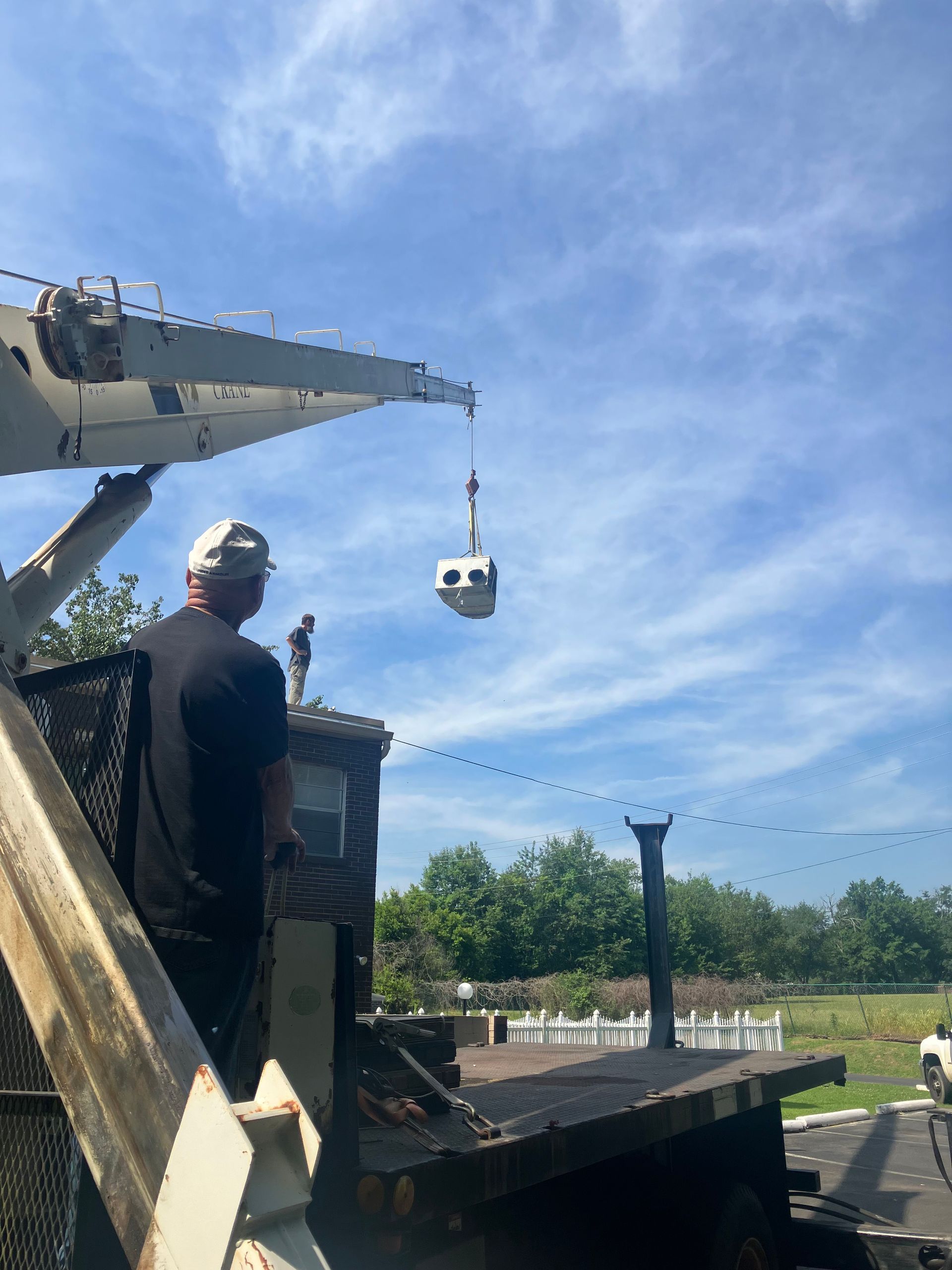 A man is standing in front of a crane that is lifting something