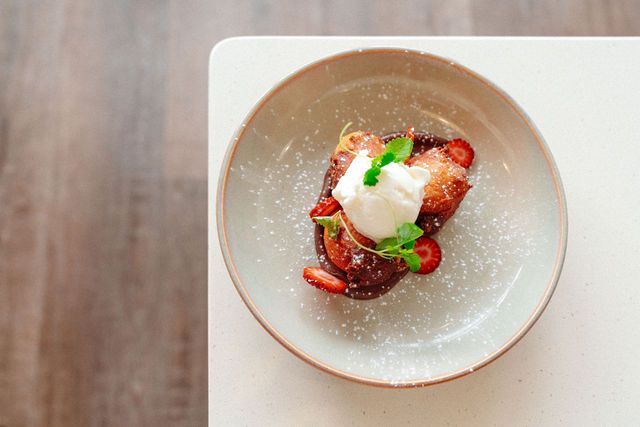A plate of food with strawberries and whipped cream on a table.