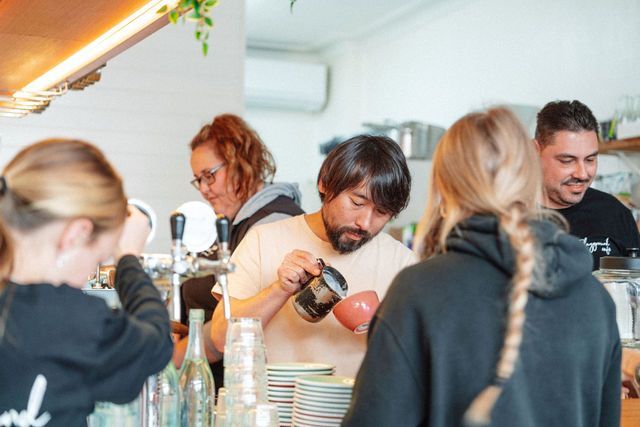 A man is pouring coffee into a cup in a restaurant.