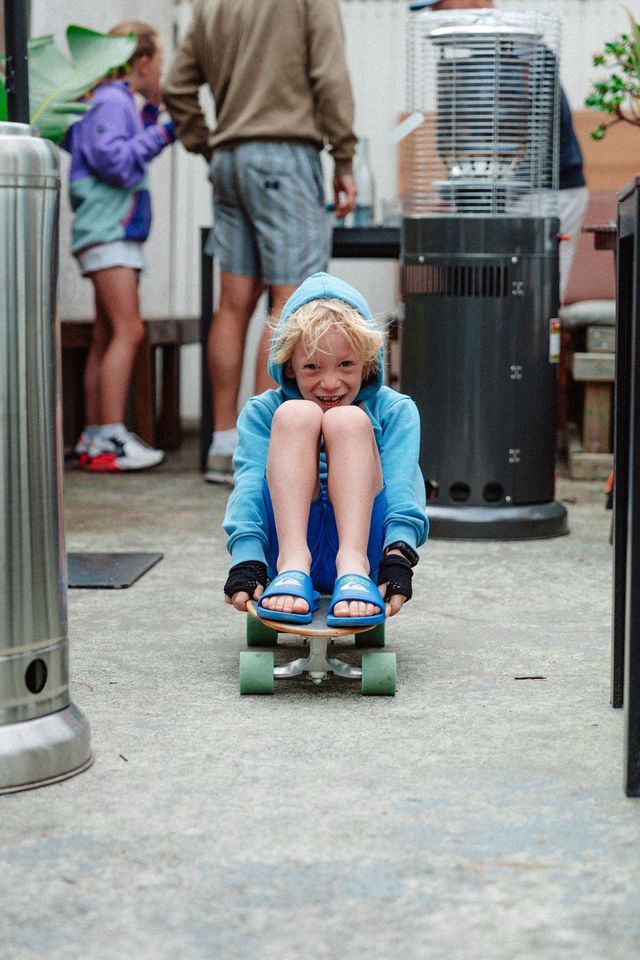 A young boy is riding a skateboard on a patio.